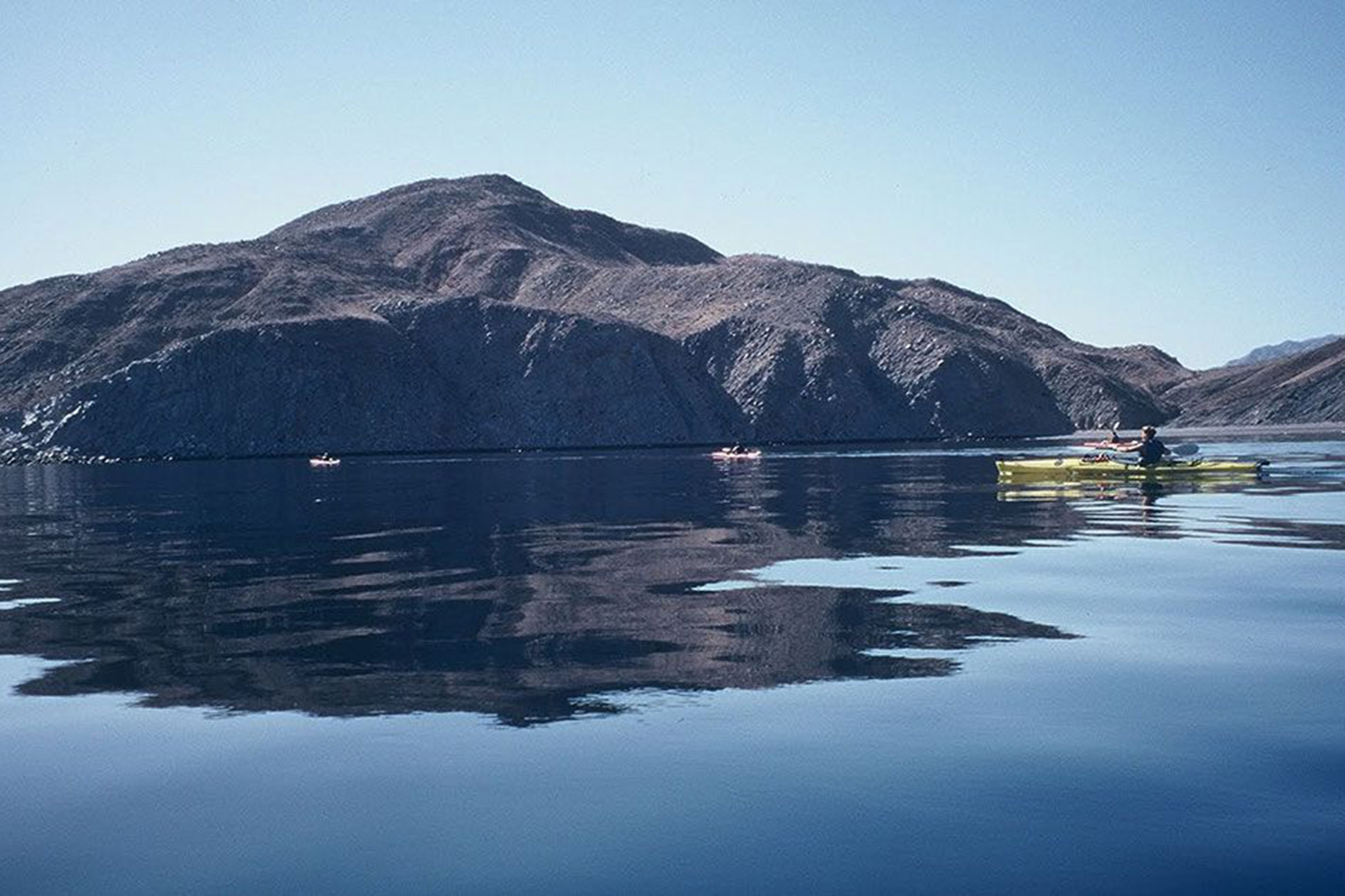 Body of water with rock formations and kayaks in distance